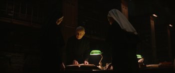 Movie still from “The Nun II” (2023), directed by Michael Chaves – A man and two women standing in front of an open book; Medium shot, Low angle