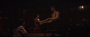 Movie still from “The Nun II” (2023), directed by Michael Chaves – A man and a woman holding hands in a dark room; Medium shot, Over the shoulder angle