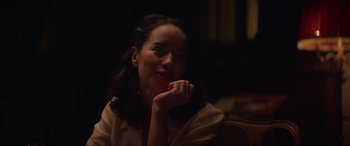 Movie still from “The Nun II” (2023), directed by Michael Chaves – A woman sitting in the dark with her hand under her chin; Close Up shot, Over the shoulder angle