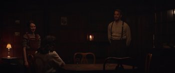Movie still from “The Nun II” (2023), directed by Michael Chaves – A man standing at a table in a dark room; Medium shot, Over the shoulder angle