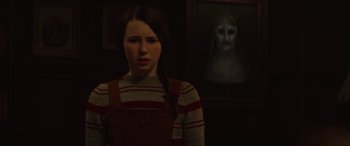 Movie still from “The Nun II” (2023), directed by Michael Chaves – A woman standing in front of a painting of a nun; Close Up shot, Over the shoulder angle