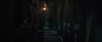Movie still from “The Nun II” (2023), directed by Michael Chaves – A person standing in a dark room under a light; Wide shot, Low angle