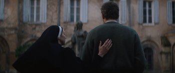 Movie still from “The Nun II” (2023), directed by Michael Chaves – A nun and a man standing next to each other in front of a building; Medium shot, Over the shoulder angle