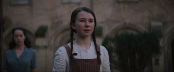 Movie still from “The Nun II” (2023), directed by Michael Chaves – A young woman with braids wearing a plaid dress; Close Up shot, Low angle