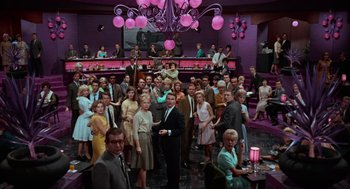 Movie still from “The Nutty Professor” (1963), directed by Jerry Lewis – A large group of people in a room with pink lights; Extreme Wide shot, High angle