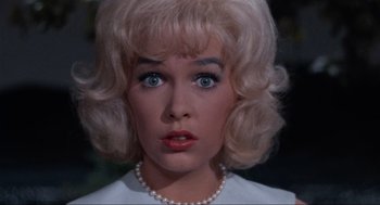 Movie still from “The Nutty Professor” (1963), directed by Jerry Lewis – A woman with blonde hair and blue eyes wearing pearls; Close Up shot, High angle