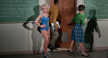 Movie still from “The Nutty Professor” (1963), directed by Jerry Lewis – A woman in a blue bathing suit standing in front of two other women; Wide shot, Over the shoulder angle