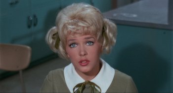 Movie still from “The Nutty Professor” (1963), directed by Jerry Lewis – A woman with blonde hair and blue eyes wearing a green bow tie; Close Up shot, High angle