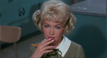 Movie still from “The Nutty Professor” (1963), directed by Jerry Lewis – A woman smoking a cigarette while holding a pencil in her mouth; Close Up shot, High angle