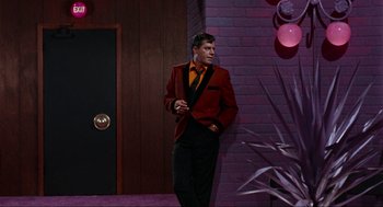 Movie still from “The Nutty Professor” (1963), directed by Jerry Lewis – A man in a red jacket and black pants standing in front of a brick wall; Medium shot, Low angle