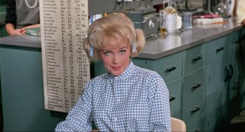 Movie still from “The Nutty Professor” (1963), directed by Jerry Lewis – A woman sitting in a chair in front of a counter; Medium shot, Low angle