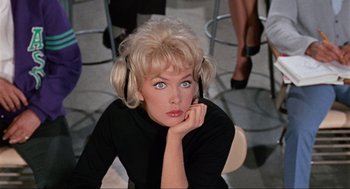 Movie still from “The Nutty Professor” (1963), directed by Jerry Lewis – A woman sitting on a chair holding a cell phone to her ear; Close Up shot, Low angle
