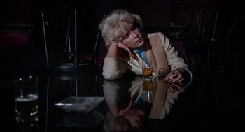 Movie still from “The Nutty Professor” (1963), directed by Jerry Lewis – A woman sitting at a table with a glass of orange juice; Medium shot, Low angle