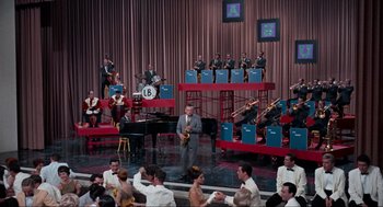 Movie still from “The Nutty Professor” (1963), directed by Jerry Lewis – A group of people sitting in front of an orchestra; Extreme Wide shot, High angle