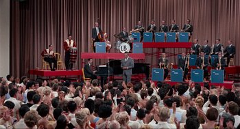 Movie still from “The Nutty Professor” (1963), directed by Jerry Lewis – A crowd of people sitting and standing in front of an orchestra; Extreme Wide shot, High angle