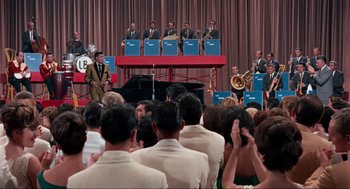 Movie still from “The Nutty Professor” (1963), directed by Jerry Lewis – A group of people sitting in front of an orchestra; Extreme Wide shot, High angle