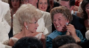 Movie still from “The Nutty Professor” (1963), directed by Jerry Lewis – Two women are laughing together at an event; Close Up shot, Over the shoulder angle