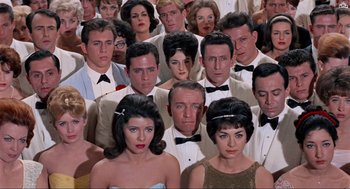 Movie still from “The Nutty Professor” (1963), directed by Jerry Lewis – A large group of people wearing tuxedos and bow ties; Medium shot, High angle