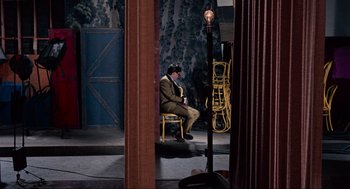 Movie still from “The Nutty Professor” (1963), directed by Jerry Lewis – A man sitting on a chair next to a lamp post; Wide shot, High angle