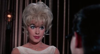 Movie still from “The Nutty Professor” (1963), directed by Jerry Lewis – A woman in a white dress with a blonde wig and blue eye shadow; Close Up shot, Over the shoulder angle