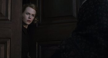 Movie still from “The Others” (2001), directed by Alejandro Amenábar – A woman standing in front of a door looking into the camera; Close Up shot, Over the shoulder angle
