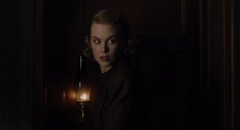 Movie still from “The Others” (2001), directed by Alejandro Amenábar – A woman holding an oil lamp in a dark room; Close Up shot, Low angle