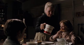 Movie still from “The Others” (2001), directed by Alejandro Amenábar – An older woman and two young children eating a meal; Medium shot, Over the shoulder angle