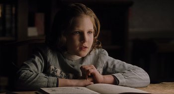 Movie still from “The Others” (2001), directed by Alejandro Amenábar – A young girl sitting in front of an open book; Close Up shot, Over the shoulder angle