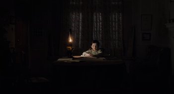 Movie still from “The Others” (2001), directed by Alejandro Amenábar – A man sitting at a table in a dark room; Medium shot, High angle