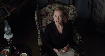 Movie still from “The Others” (2001), directed by Alejandro Amenábar – A woman sitting in a chair holding a plate; Medium shot, Low angle