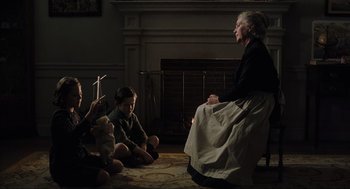 Movie still from “The Others” (2001), directed by Alejandro Amenábar – An old woman sitting on the ground with two young boys; Medium shot, Over the shoulder angle