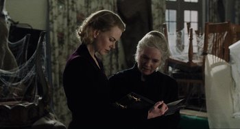 Movie still from “The Others” (2001), directed by Alejandro Amenábar – Two women are looking at a piece of paper together; Medium shot, High angle