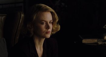 Movie still from “The Others” (2001), directed by Alejandro Amenábar – A woman with blonde hair sitting in a dark room; Close Up shot, Over the shoulder angle