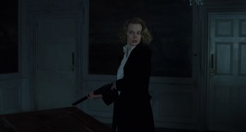 Movie still from “The Others” (2001), directed by Alejandro Amenábar – A woman in a black jacket holding a gun; Medium shot, Low angle