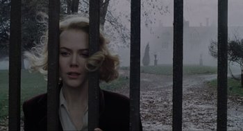 Movie still from “The Others” (2001), directed by Alejandro Amenábar – A woman standing in front of a fence; Medium shot, Low angle