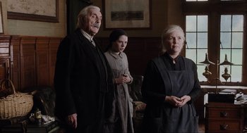 Movie still from “The Others” (2001), directed by Alejandro Amenábar – Two women and an old man standing next to each other in a room; Medium shot, Low angle
