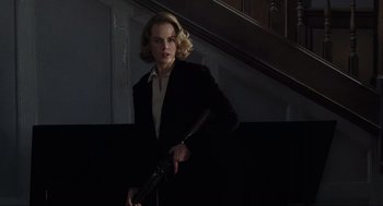 Movie still from “The Others” (2001), directed by Alejandro Amenábar – A woman holding a gun in a dark room; Medium shot, Low angle