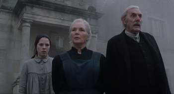 Movie still from “The Others” (2001), directed by Alejandro Amenábar – A group of people standing next to each other in front of a building; Medium shot, Low angle