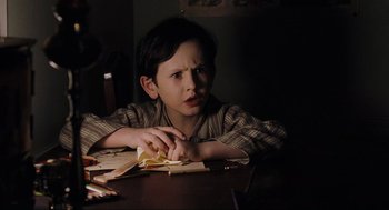 Movie still from “The Others” (2001), directed by Alejandro Amenábar – A boy sitting at a table holding a piece of paper; Close Up shot, High angle