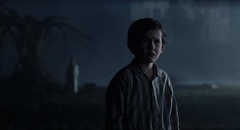Movie still from “The Others” (2001), directed by Alejandro Amenábar – A young boy standing in the dark in front of a statue; Medium shot, Over the shoulder angle