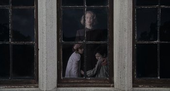 Movie still from “The Others” (2001), directed by Alejandro Amenábar – A woman and two children looking out of a window; Medium shot, Low angle