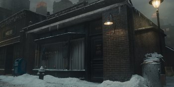 Movie still from “The Outfit” (2022), directed by Graham Moore – A brick building with a street light hanging from the side of the building; Extreme Wide shot, High angle