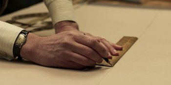 Movie still from “The Outfit” (2022), directed by Graham Moore – A person is holding a ruler and a pencil; Extreme Close Up shot, Low angle