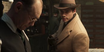 Movie still from “The Outfit” (2022), directed by Graham Moore – A man wearing a hat and a coat; Medium shot, Over the shoulder angle