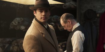Movie still from “The Outfit” (2022), directed by Graham Moore – A man wearing a hat and a coat; Medium shot, Low angle