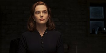 Movie still from “The Outfit” (2022), directed by Graham Moore – A woman in a black shirt is standing in front of a brick wall; Close Up shot, Low angle
