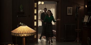 Movie still from “The Outfit” (2022), directed by Graham Moore – A man and a woman are walking through a doorway; Wide shot, Over the shoulder angle