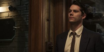 Movie still from “The Outfit” (2022), directed by Graham Moore – A man in a suit and tie standing in front of a door; Close Up shot, Low angle