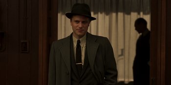 Movie still from “The Outfit” (2022), directed by Graham Moore – A man wearing a suit and tie and a hat; Medium shot, Low angle