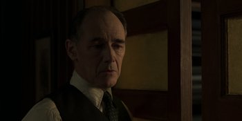 Movie still from “The Outfit” (2022), directed by Graham Moore – An older man wearing a suit and tie; Close Up shot, Low angle